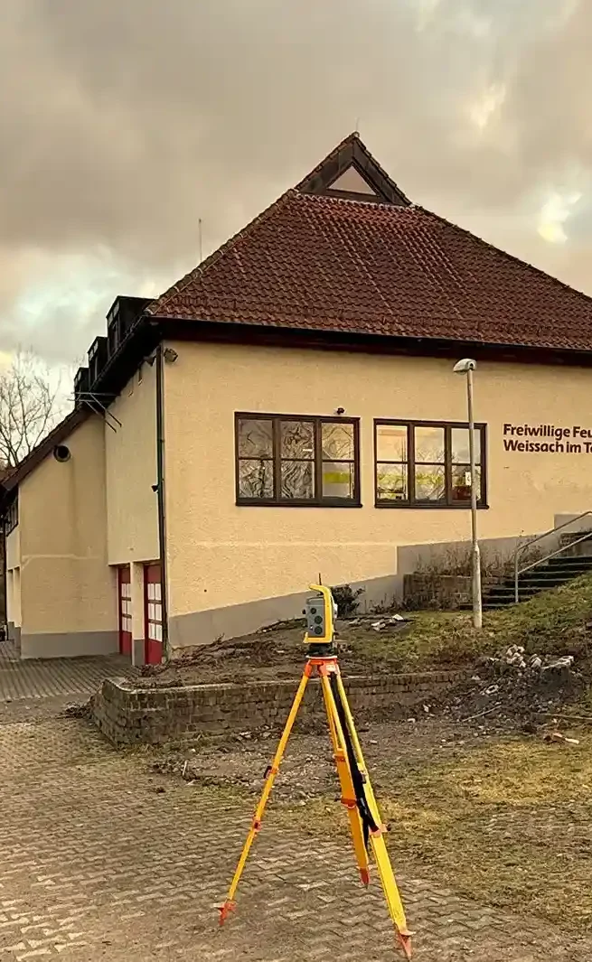Vermessungsgerät auf einem Stativ vor einem Gebäude der Freiwilligen Feuerwehr in Weissach im Tal.