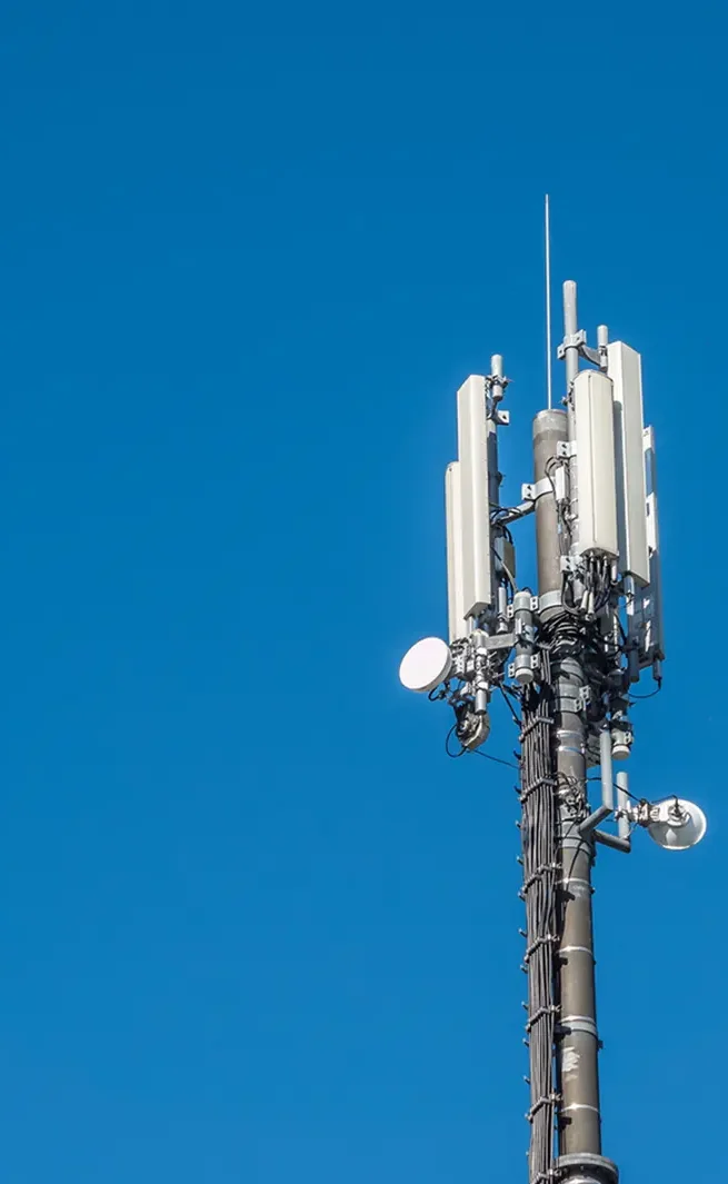 Mobilfunkmast mit mehreren Antennen und einer klaren blauen Himmel im Hintergrund.