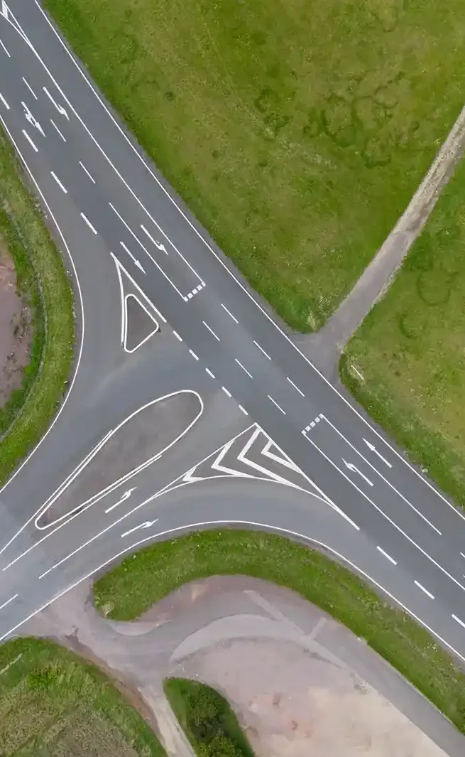 Luftaufnahme einer Kreuzung mit mehreren Fahrspuren und angrenzenden Grünflächen.